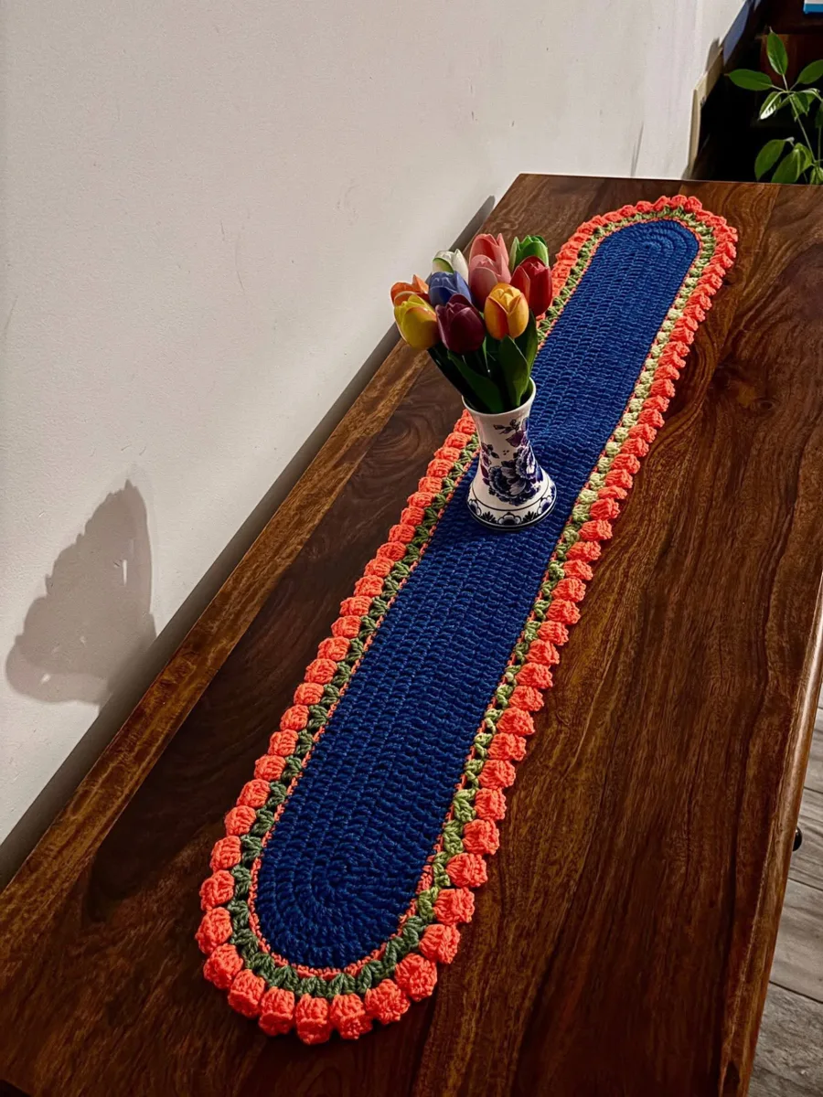 Tulip blue table runner Tulip blue table runner, handmade crochet by Atelier Annamaria. Royal blue runner with coral bobbles and a green trim.