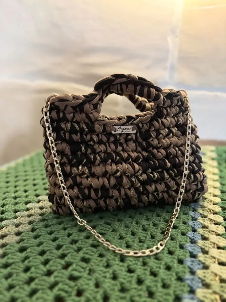 Anjore Cocoa chain bag Anjore Cocoa chain bag, handmade crochet by Atelier Annamaria. Brown and black chunky bag with a gold chain.